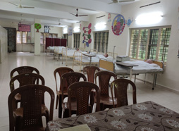 Spacious nursing skills lab with rows of plastic chairs, hospital beds, and training manikins under ceiling fans.